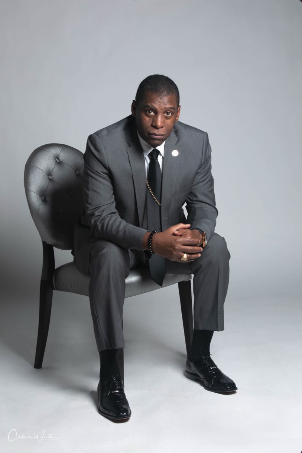 Bishop Douglas seated in a grey suit, looking thoughtfully at the camera